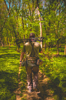 a man walking with the saddle hunting kit from BullPath in the woods