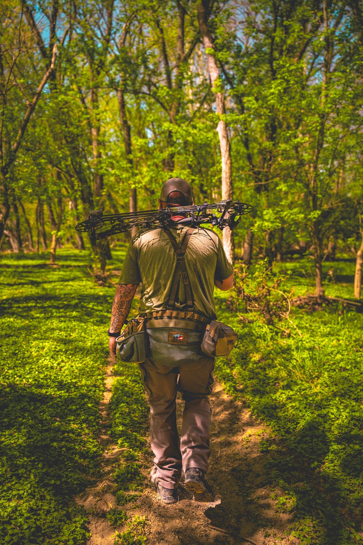 a man walking with the saddle hunting kit from BullPath in the woods