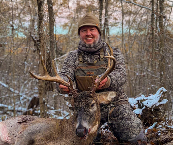 a man holding up a buck while wearing the BullPath Moose Chest Rig