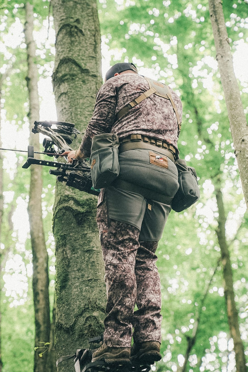 Load image into Gallery viewer, Hunter standing on tree steps wearing the BullPath El Toro hunting saddle with gear pouches attached, ready to draw
